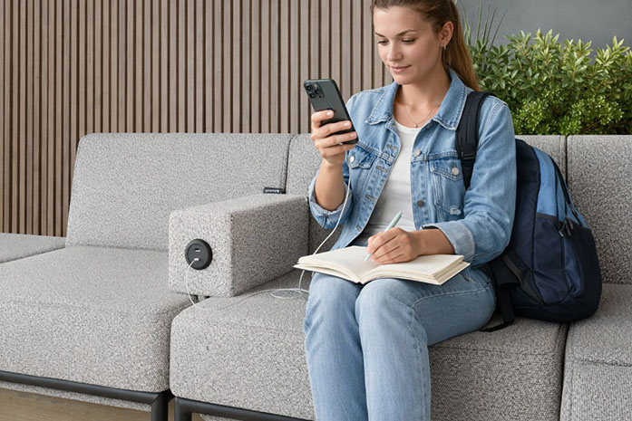 student sitting on lounge seating charging her phone